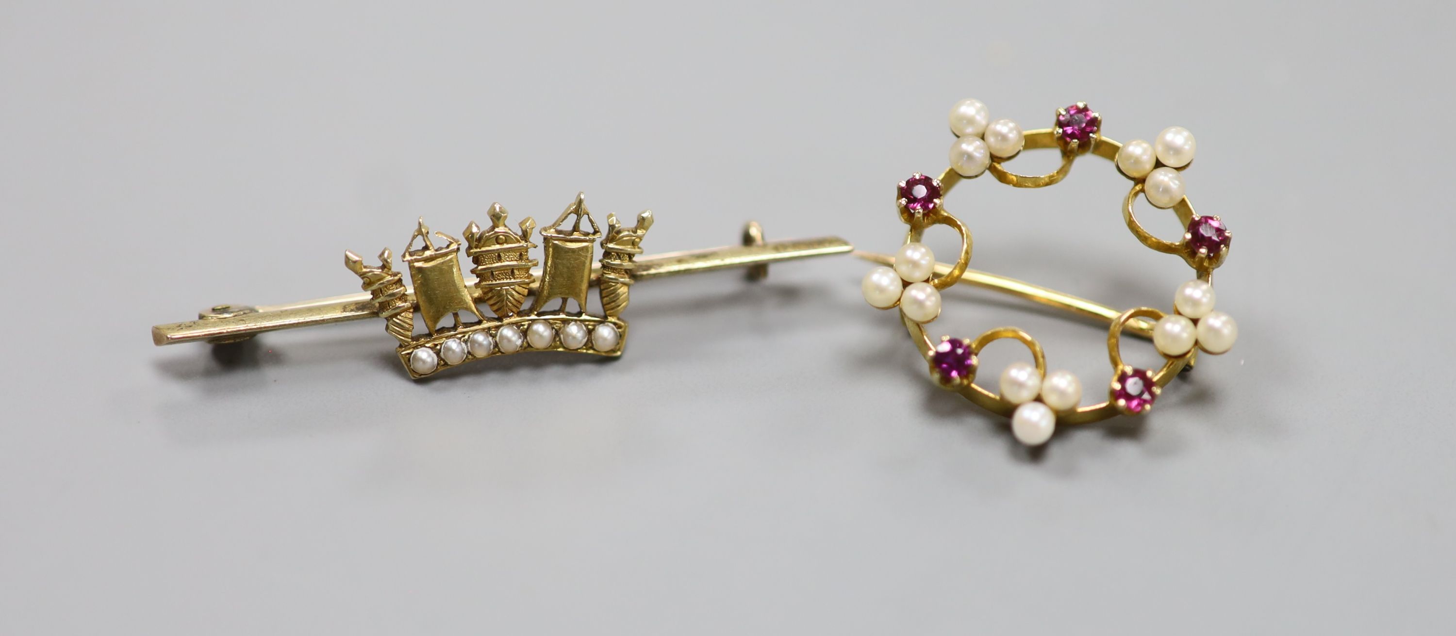 A French yellow metal (18ct poincon mark), seed pearl and ruby set openwork circular brooch, 22mm gross 3.7 grams and a yellow metal and seed pearl set coronet bar brooch, 45mm, gross 4.4 grams.